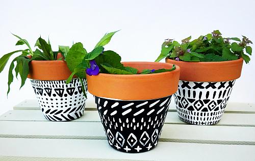 A trio of flower pots painted with black and white designs
