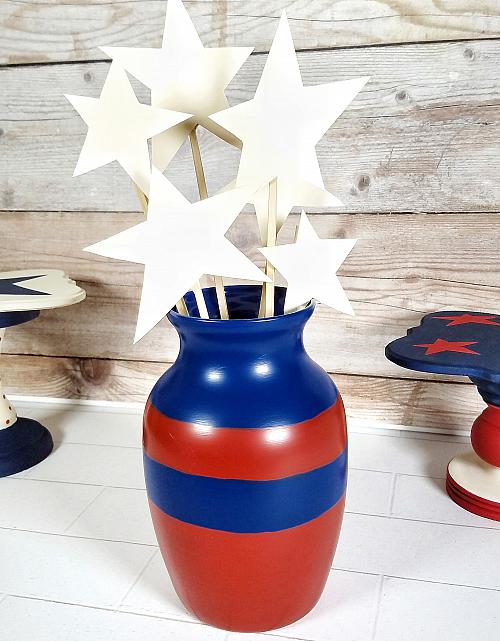 A vase painted with red and blue stripes and filled with white stars on sticks