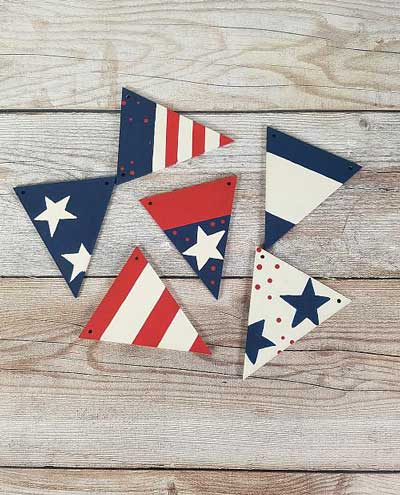 Triangles painted in various red, white, and blue patterns waiting to be assembled into a banner for the 4th of July.