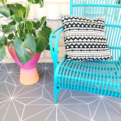 A concrete patio is painted with stencils to look like faux tile