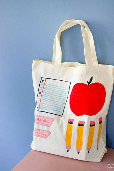 A tote bag with school supplies painted on them.