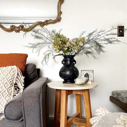 A vase painted black and set up in a living room.