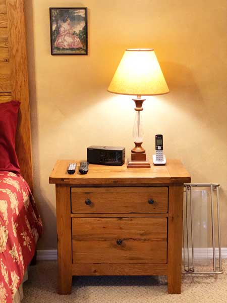 A picture of an old-fashioned looking lamp with a dingy lampshade sitting on a bedside table.