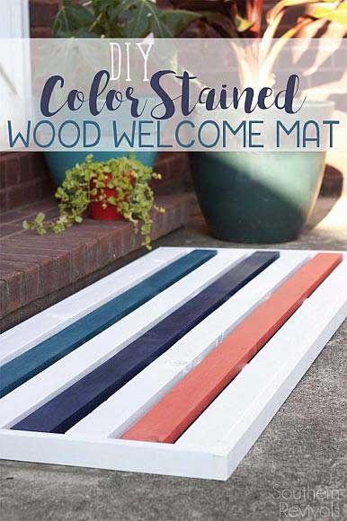 A door mat is made of wooden slats painted with color stain for a colorful striped look