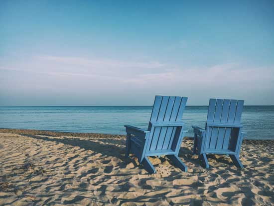 A picture of blue beach chairs on a beach facing towards the ocean.