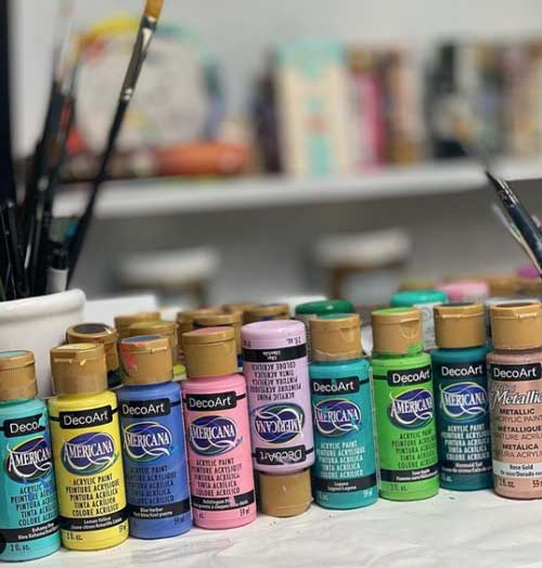 A line up of various DecoArt americana acrylic paint bottles.