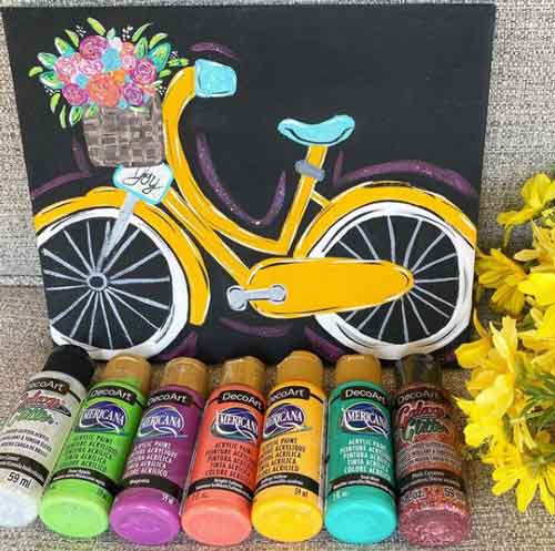 A canvas painting of a bicycle done using DecoArt acrylic paint.