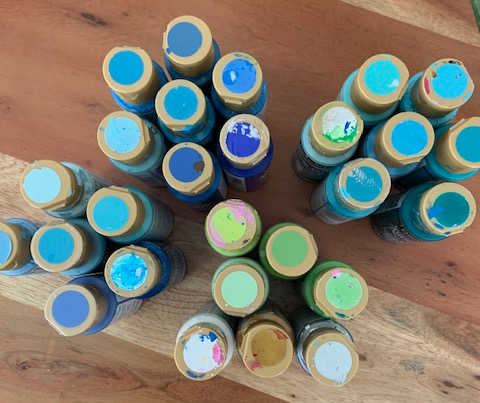 Multiple bottles of blue and green DecoArt paint
