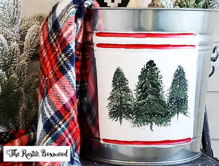A steel bucket with pine trees painted on it