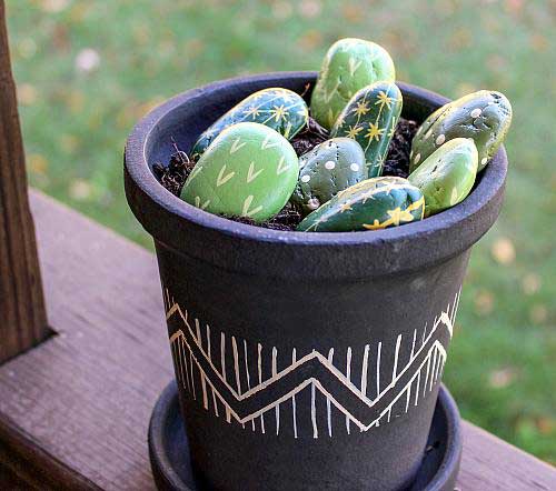 A flower planter filled with rocks painted to look like cacti.