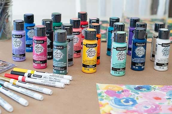 A line-up of DecoArt glass paint and glass paint markers in a variety of colors.