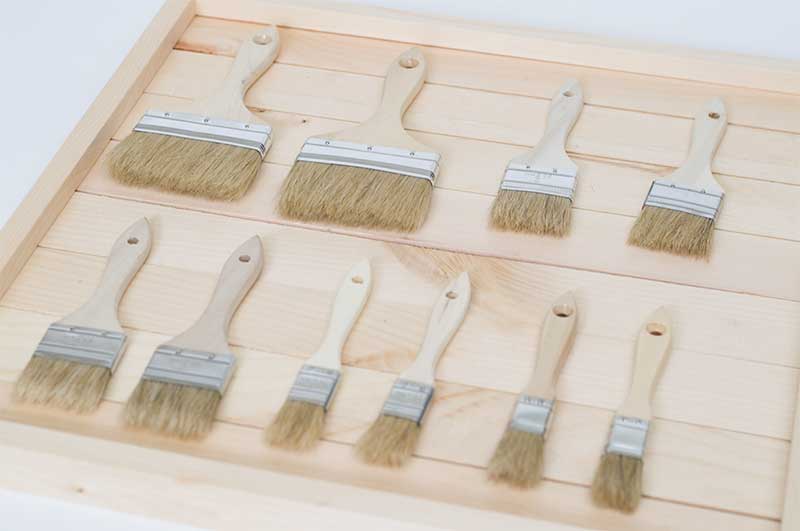 A bunch of flat paintbrushes in various sizes are laid out