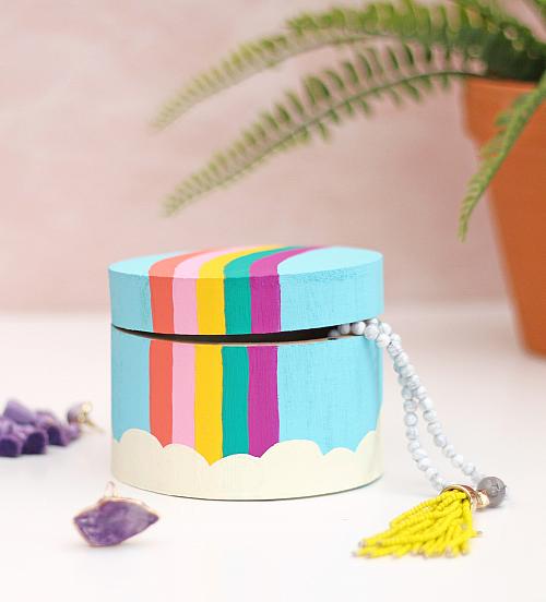 A wooden jewelry box painted with a pastel rainbow 