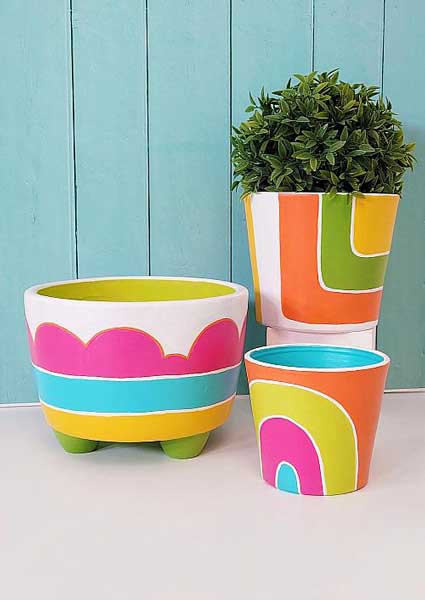 Colorful and bright flower planters are painted in rainbow stripes