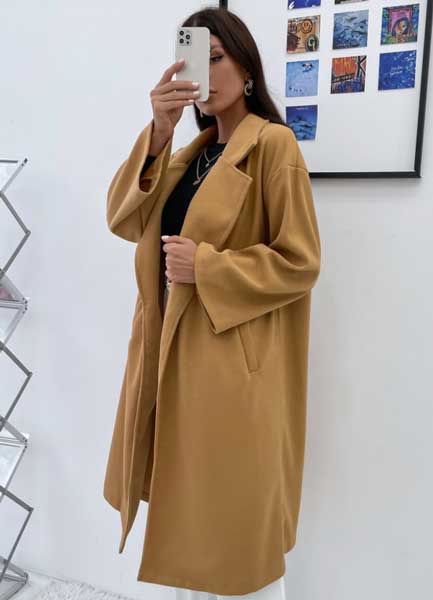 A woman taking a selfie wearing a honey brown trench coat