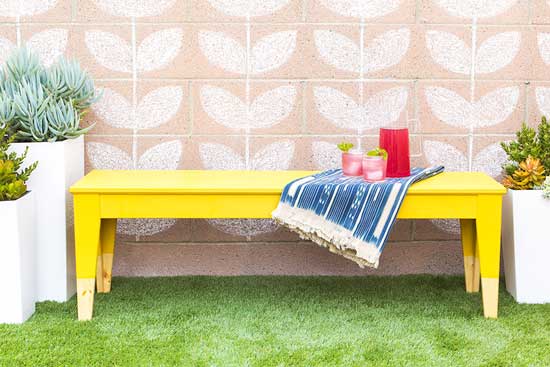 An IKE bench is given a makeover using sunshine yellow acrylic paint.