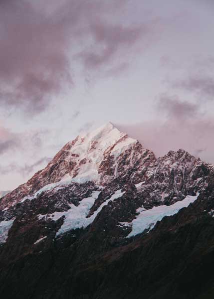 A snowy mountaintop in the distance during dusk, the sky is a gorgeous lavender color.