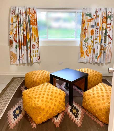 A living room with white fabric curtains painted in a colorful design with broad brushstroke patterns.