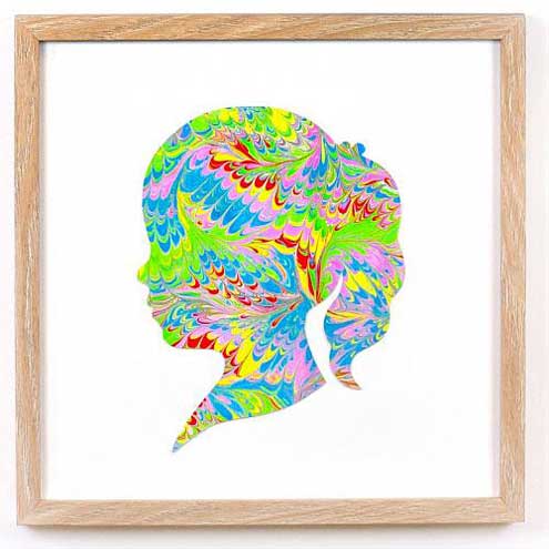 A silhouette of a young girl made out of water marbled paper and hung up in a frame.