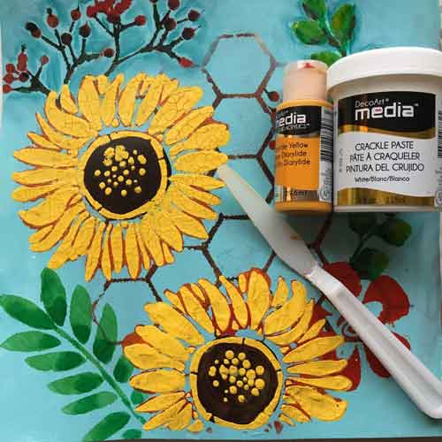 A mixed media journal where sunflowers are being painted inside using acrylic paint.