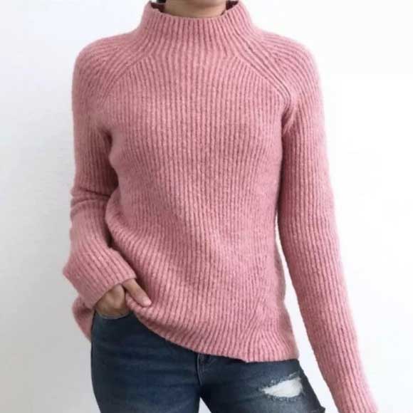 A woman stands facing forward wearing a fuzzy pink heather sweatshirt