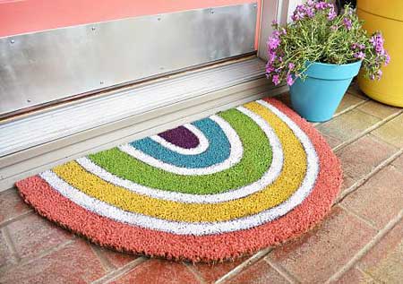 An oval doormat is painted in stripes to look like a rainbow.