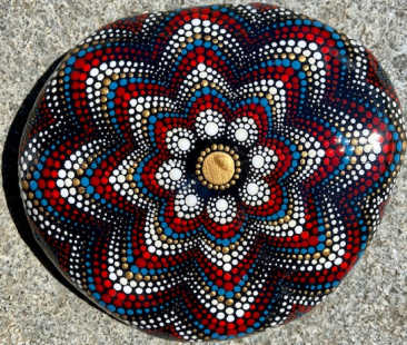 A red, white, and blue mandala pattern painted on a stone