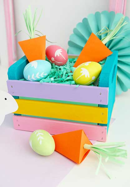 A mini wooden crate is decorated in pastel spring colors and filled with Easter grass