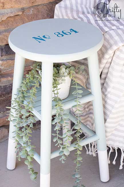 A wooden stool is repainted and repurposed into an outdoor end table.